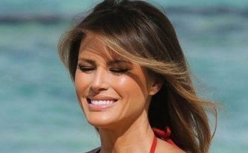 woman in red bikini smiling at sunny beach, eyes closed