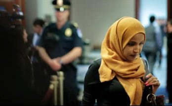 woman in yellow hijab in hallway with police presence