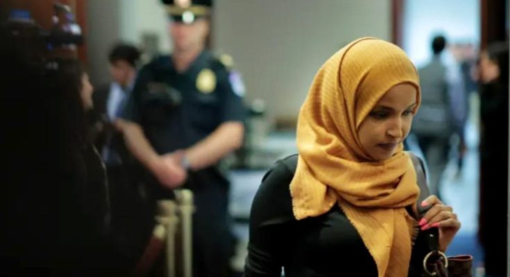 woman in yellow hijab in hallway with police presence