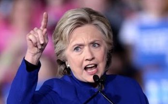 hillary Clinton speaking passionately at a public event, blue outfit