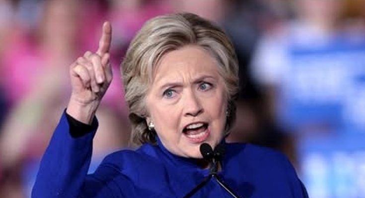 hillary Clinton speaking passionately at a public event, blue outfit