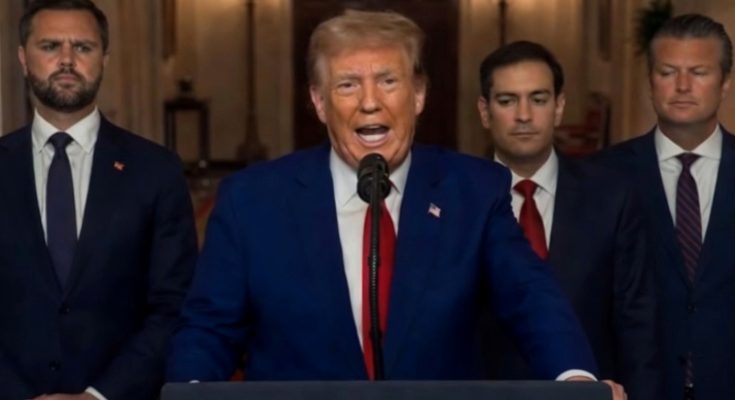 politician delivers speech flanked by serious men in suits